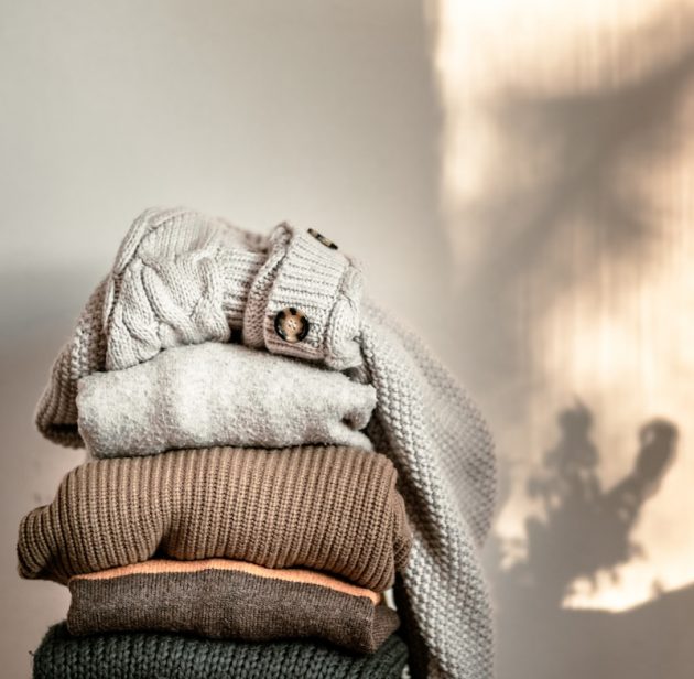 a stack of sweaters sitting on top of a wooden chair